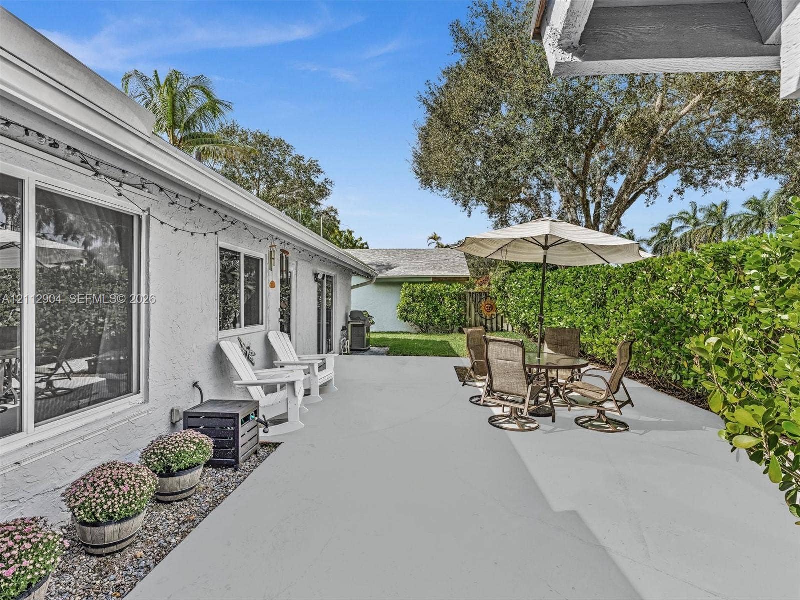 76 Forest Circle, Cooper City, FL 33026 Concrete patio featuring painted finish, stucco exterior walls, sliding glass doors, and mature hedge perimeter