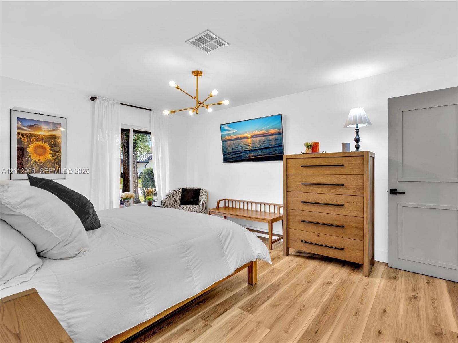 76 Forest Circle, Cooper City, FL 33026 Wood-finish flooring, multi-arm brass chandelier, and grey-toned shaker-style interior door with matte black hardware