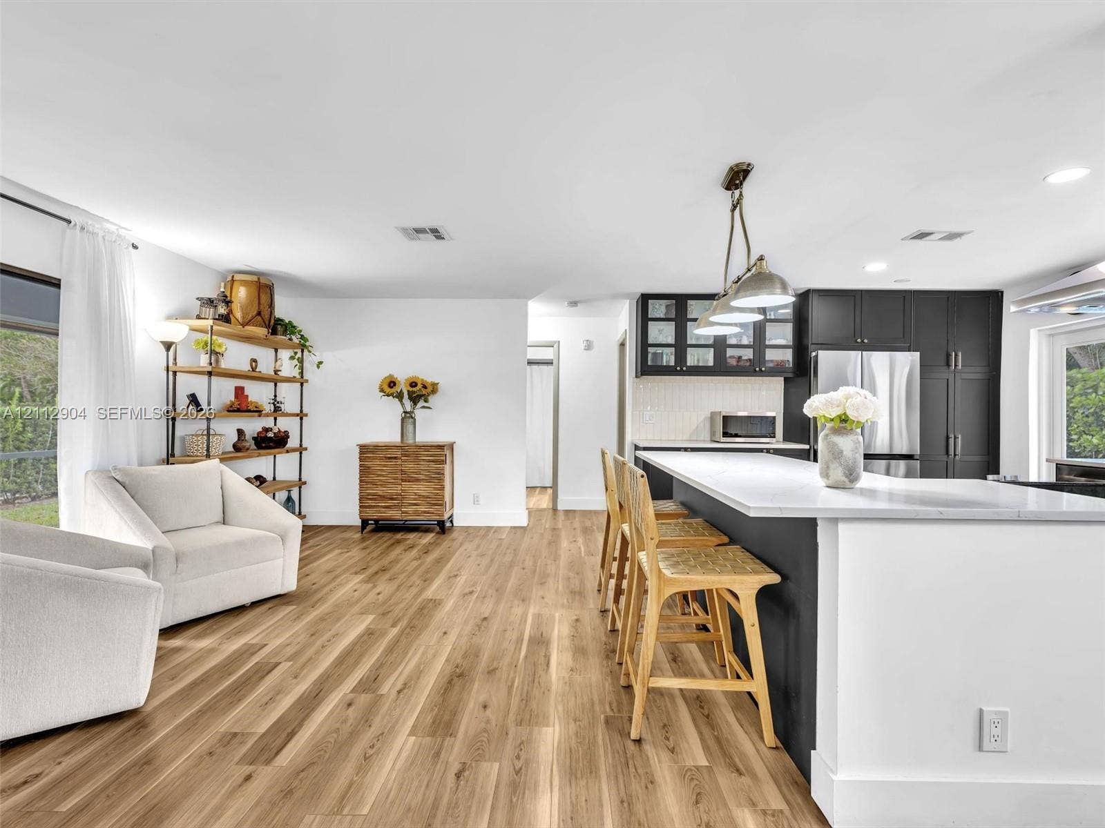 76 Forest Circle, Cooper City, FL 33026 Open-concept kitchen featuring a large central island with quartz countertops, dark cabinetry, recessed lighting, and wood-finish flooring