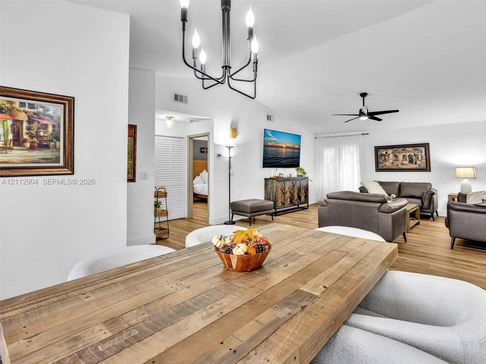 76 Forest Circle, Cooper City, FL 33026 Open-concept living space featuring vaulted ceilings, wood-finish flooring, a multi-arm chandelier, and a black ceiling fan