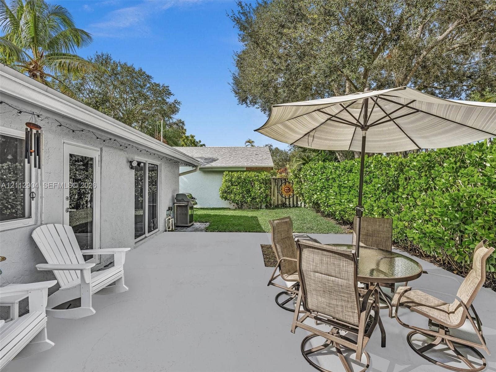 76 Forest Circle, Cooper City, FL 33026 Concrete patio featuring sliding glass doors and manicured hedge perimeter