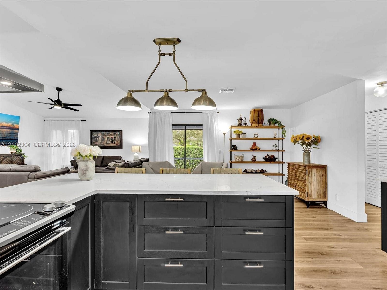 76 Forest Circle, Cooper City, FL 33026 Kitchen featuring an L-shaped island with stone-finish countertops, matte black shaker-style cabinetry, wood-finish flooring, and a three-light metal pendant fixture