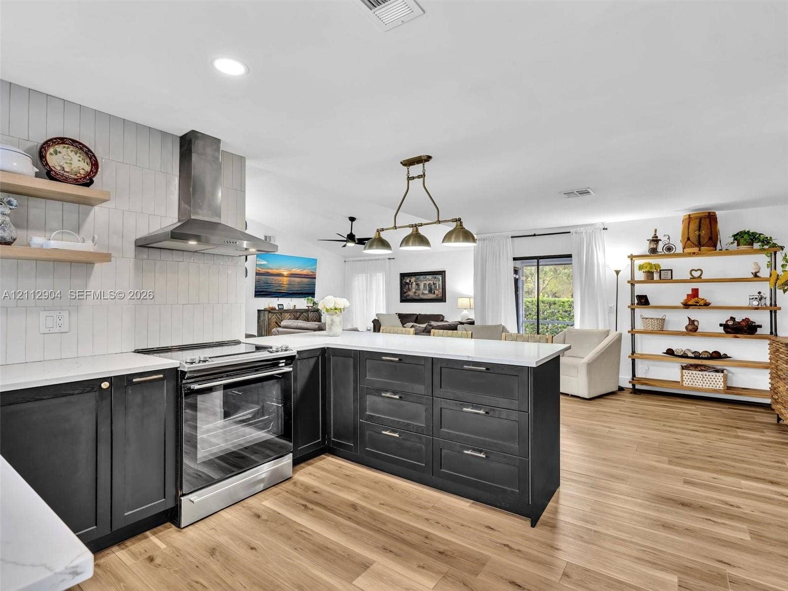 76 Forest Circle, Cooper City, FL 33026 Kitchen featuring dark cabinetry, white countertops, vertical tile backsplash, stainless steel range with overhead hood, and wood-finish flooring