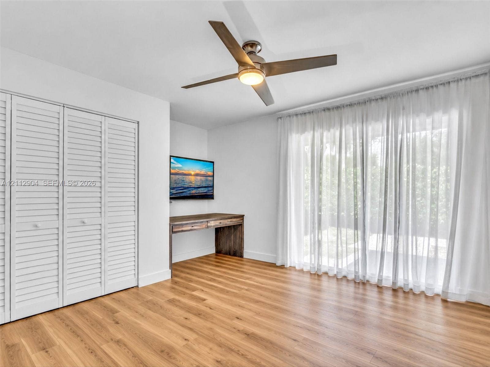 76 Forest Circle, Cooper City, FL 33026 Wood-finish flooring, white louvered-style closet doors, modern ceiling fan with integrated lighting, and floor-to-ceiling glass sliding doors