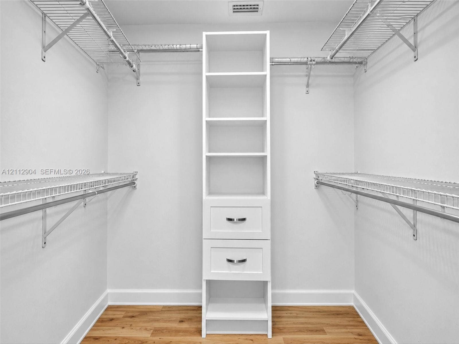 76 Forest Circle, Cooper City, FL 33026 Walk-in closet featuring wood-finish flooring, white built-in cabinetry with two storage drawers, and dual-level metal wire shelving