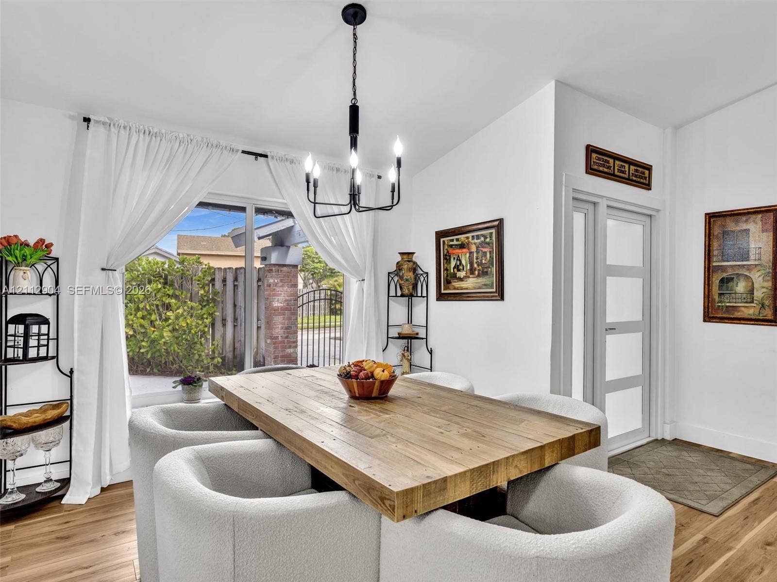 76 Forest Circle, Cooper City, FL 33026 Dining area featuring wood-finish flooring, a five-light matte black chandelier, and a multi-panel glass door with frosted inserts
