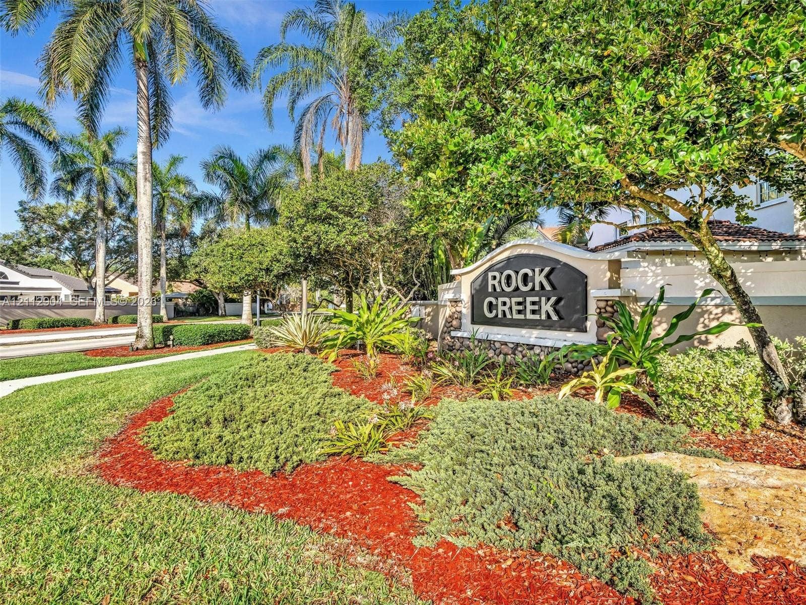 76 Forest Circle, Cooper City, FL 33026 Community signage featuring stone-accented monument base, mature palm trees, established tropical landscaping, and expansive green space