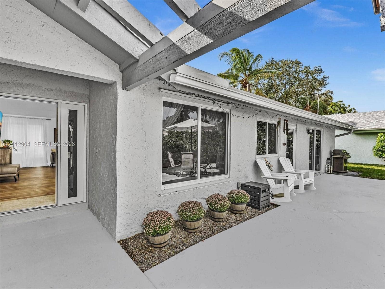 76 Forest Circle, Cooper City, FL 33026 Stucco exterior patio featuring a wood-beam pergola, concrete flooring, and a stone-lined garden bed