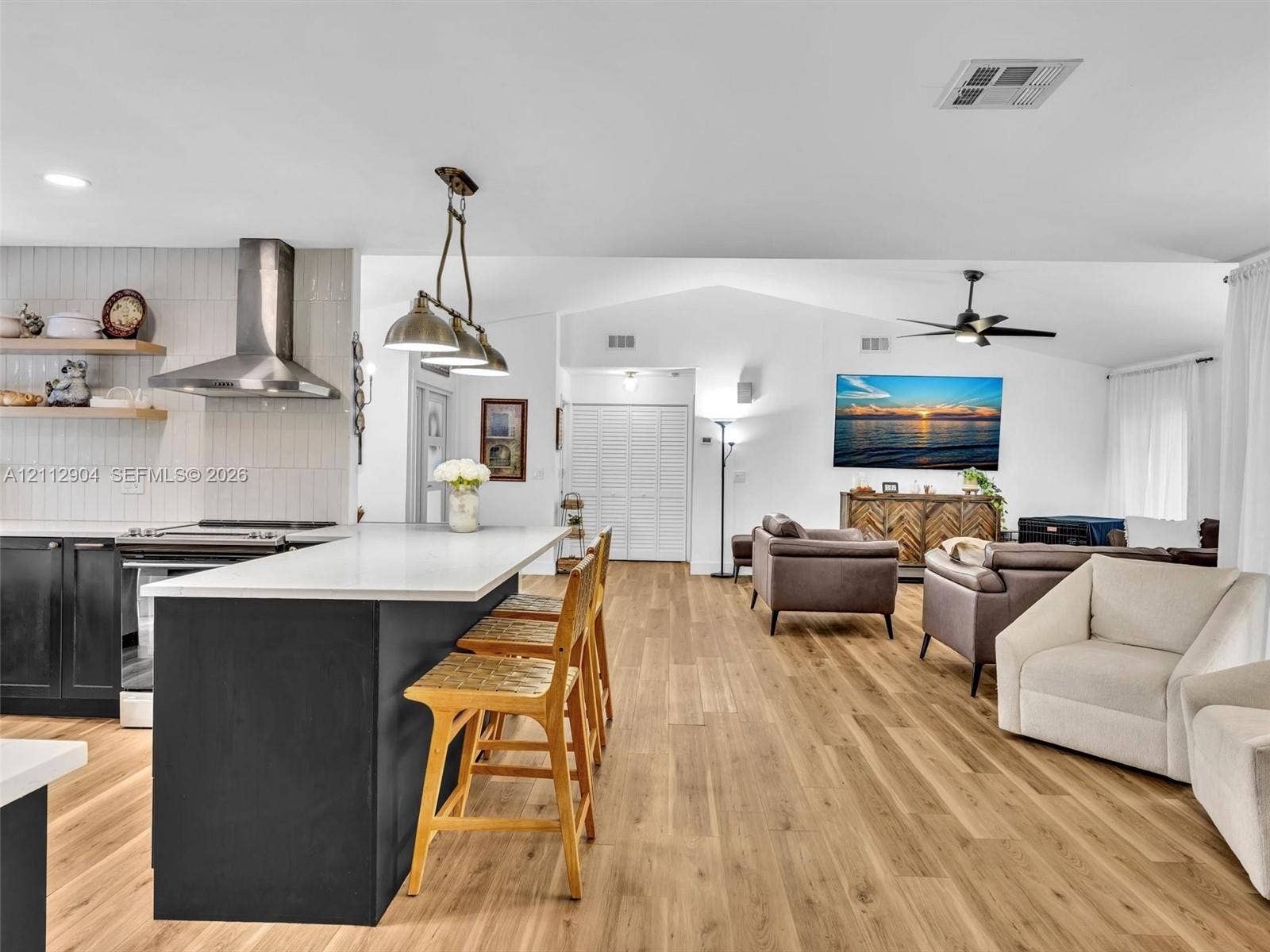 76 Forest Circle, Cooper City, FL 33026 Kitchen featuring a central island with a quartz countertop, stainless steel range hood, vertical tiled backsplash, wood-finish flooring, and industrial-style pendant lighting