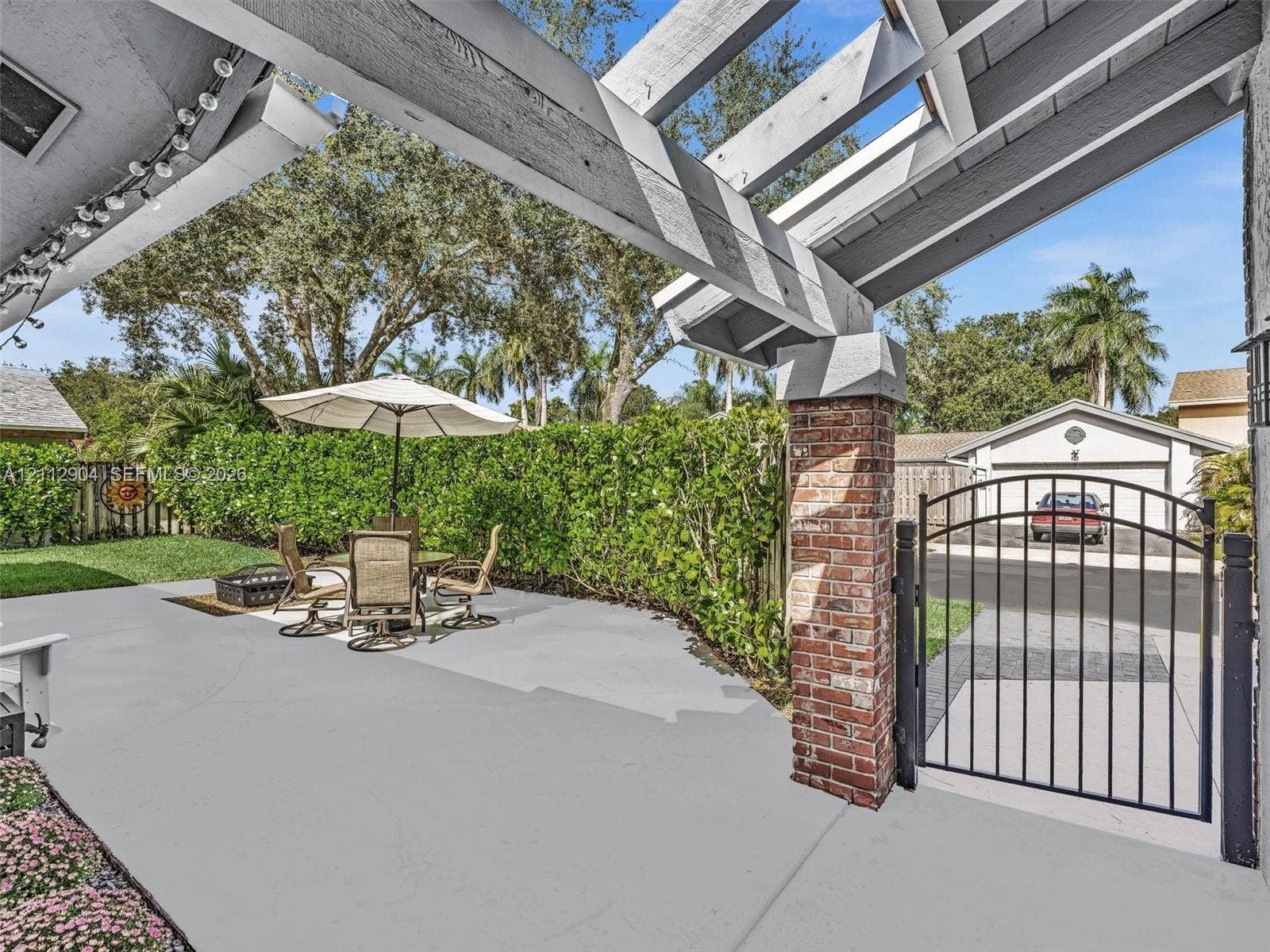 76 Forest Circle, Cooper City, FL 33026 Covered patio featuring a timber-frame pergola, brick-pillar architectural detailing, and a black metal pedestrian gate