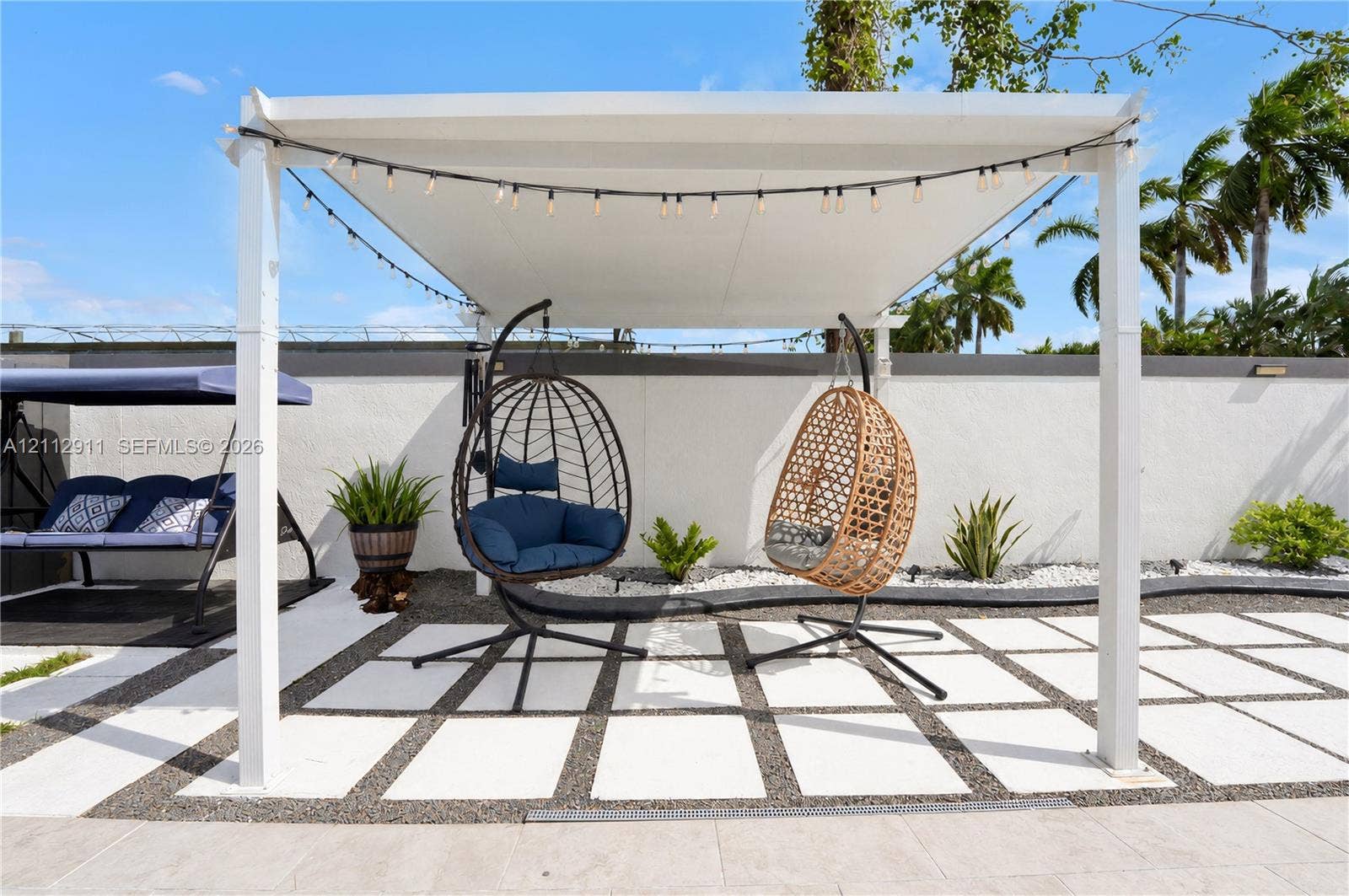 217 SW 15th Place, Homestead, FL 33030 Outdoor patio featuring a white pergola, large-format concrete pavers, decorative gravel inlay, and a perimeter stucco wall