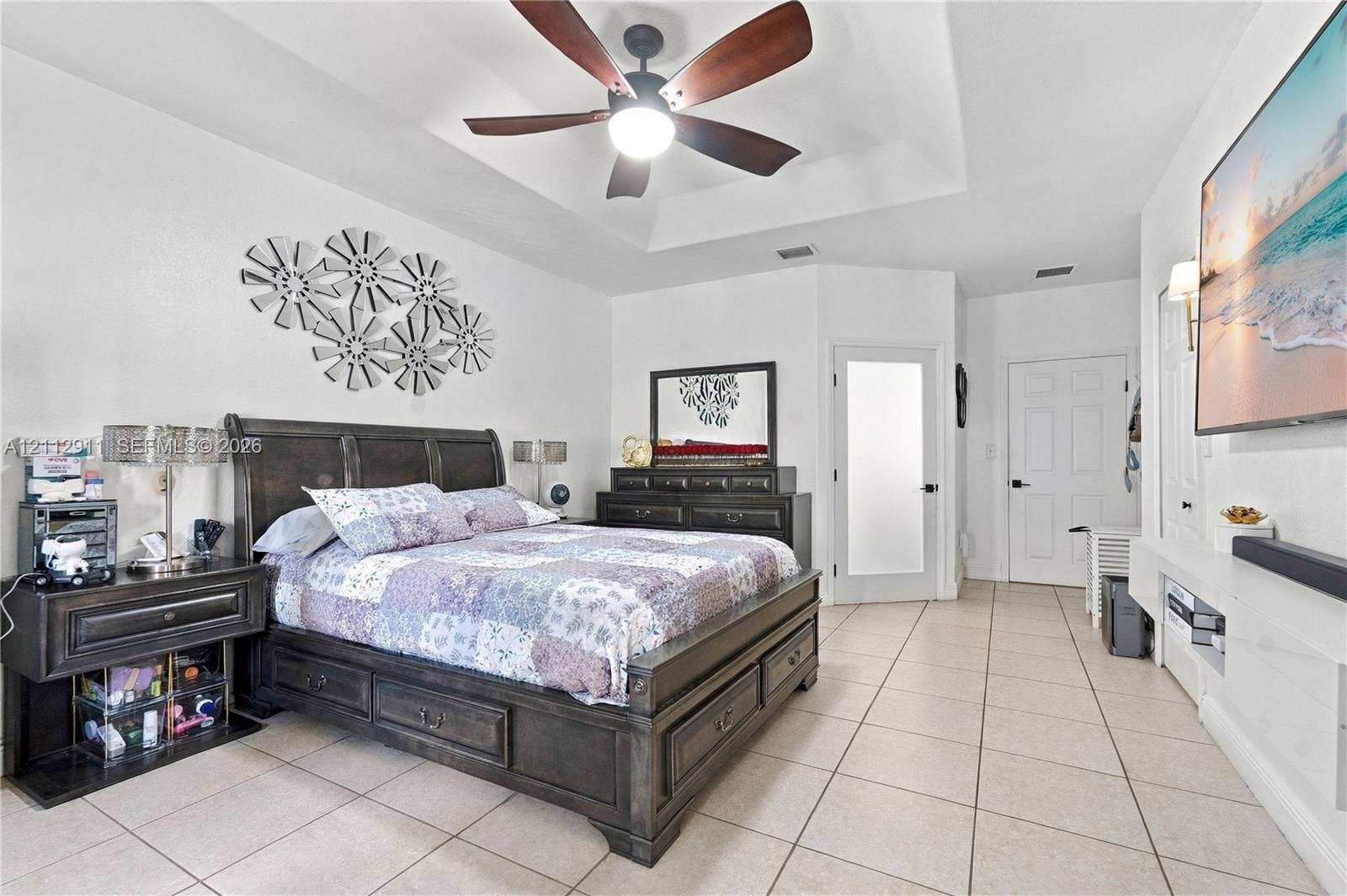 217 SW 15th Place, Homestead, FL 33030 Tray ceiling with a central multi-blade ceiling fan, neutral tile flooring, and frosted glass paneled door