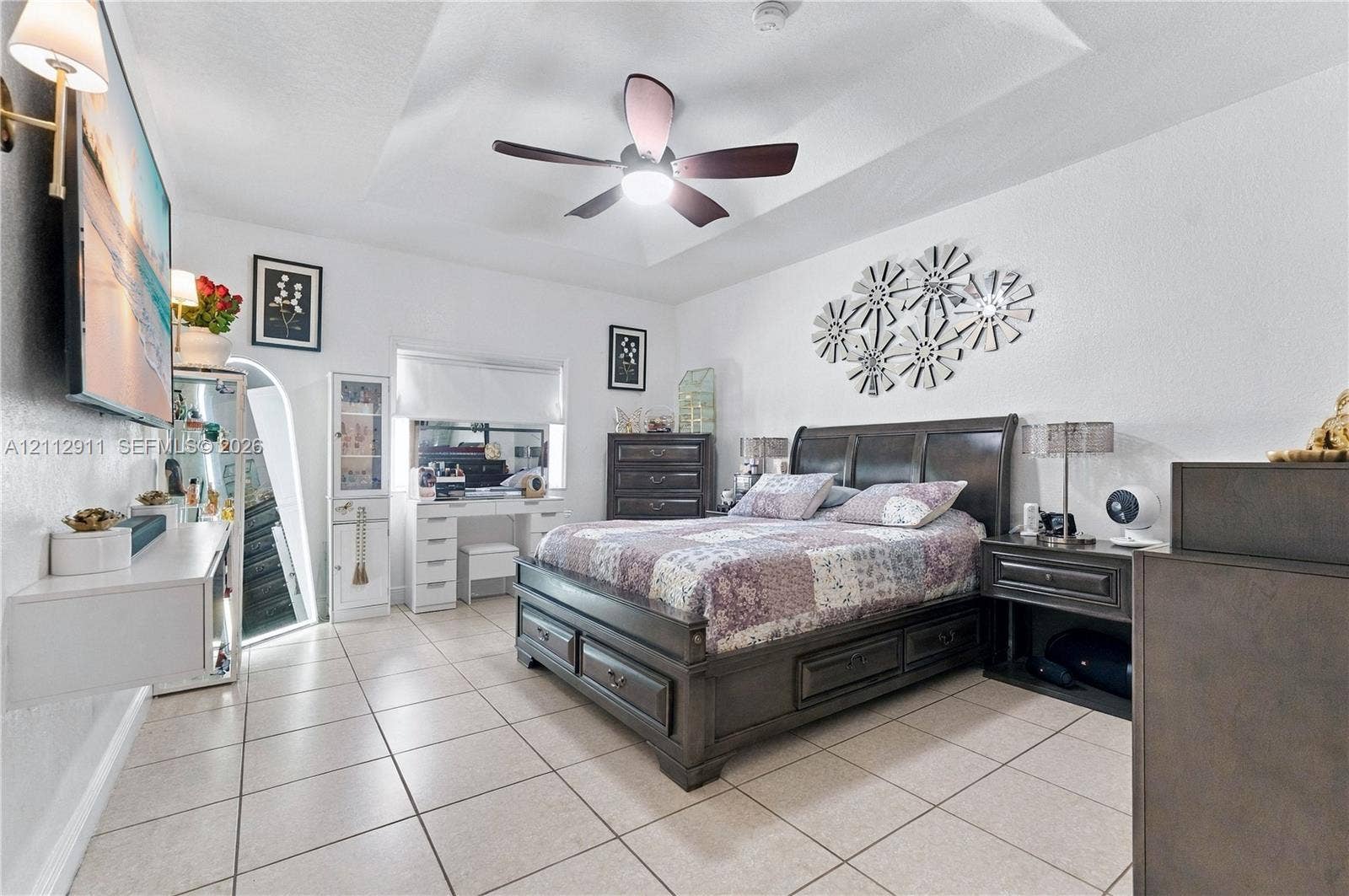217 SW 15th Place, Homestead, FL 33030 Tray ceiling featuring a central lighted ceiling fan, complemented by tile flooring, an arched mirror installation, and wall-mounted lighting fixtures