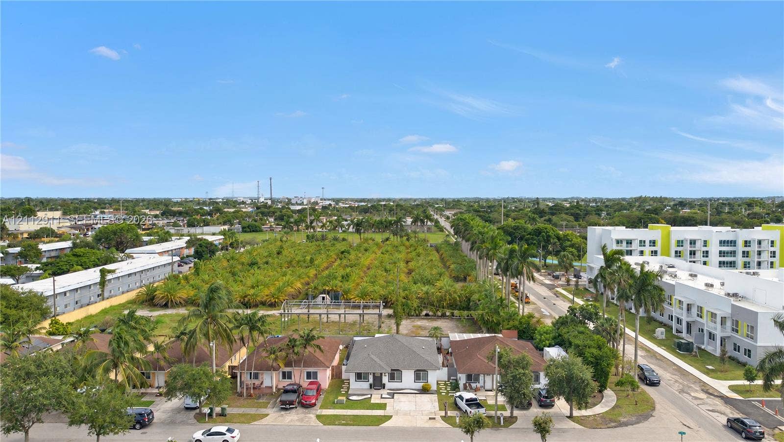 217 SW 15th Place, Homestead, FL 33030 Aerial perspective featuring a single-story residence with a pitched roof, paved driveway, expansive level lot, and mature palm landscaping