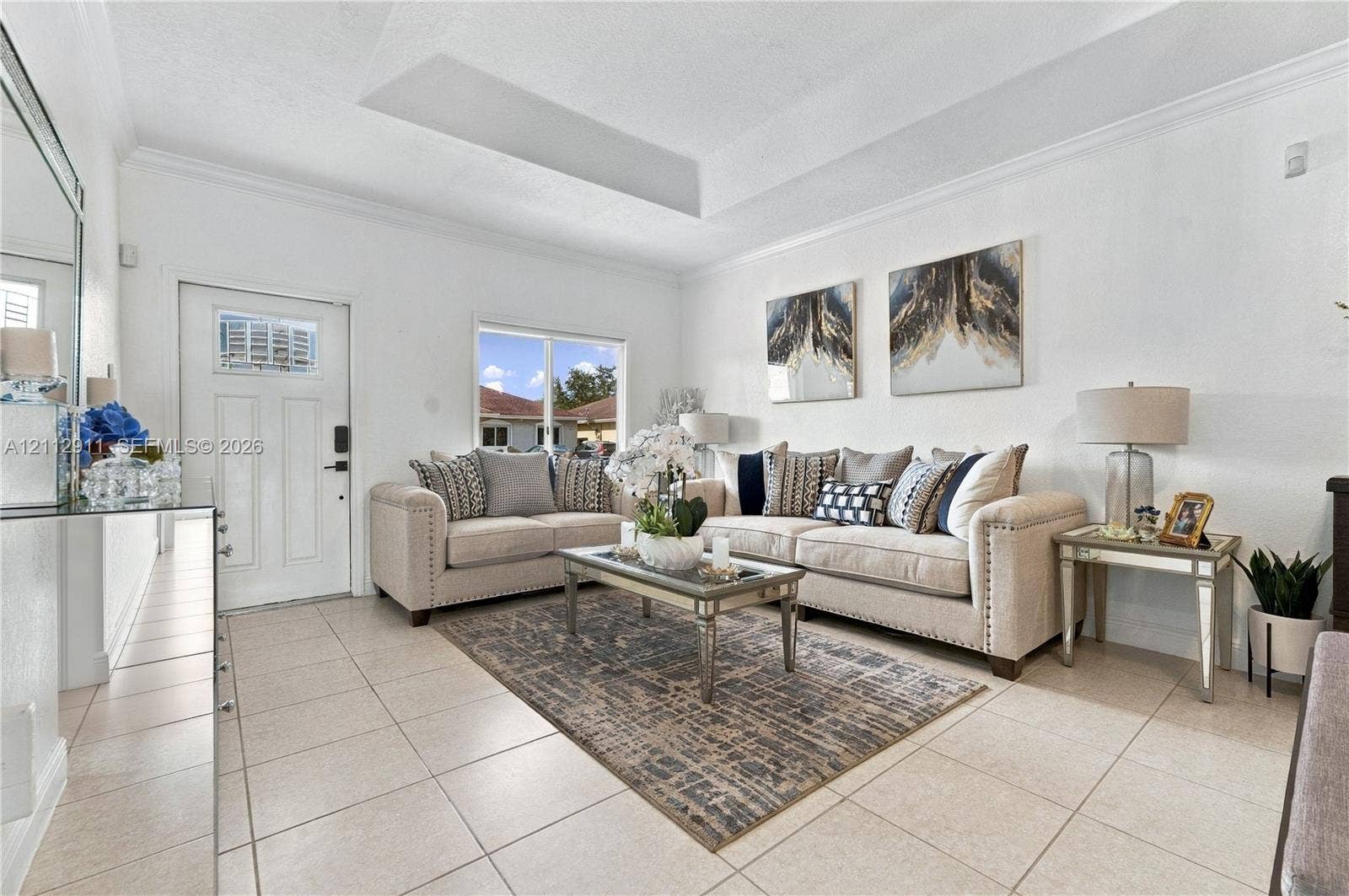217 SW 15th Place, Homestead, FL 33030 Interior space featuring ceramic tile flooring, a tray ceiling, crown molding, and a multi-panel entry door with an integrated window