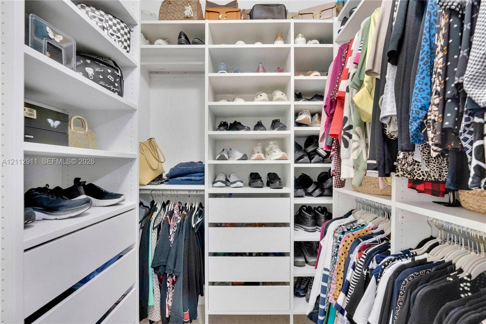 217 SW 15th Place, Homestead, FL 33030 Custom walk-in closet featuring white built-in cabinetry, multiple adjustable shelving tiers, integrated drawer storage, and dual-level hanging rods