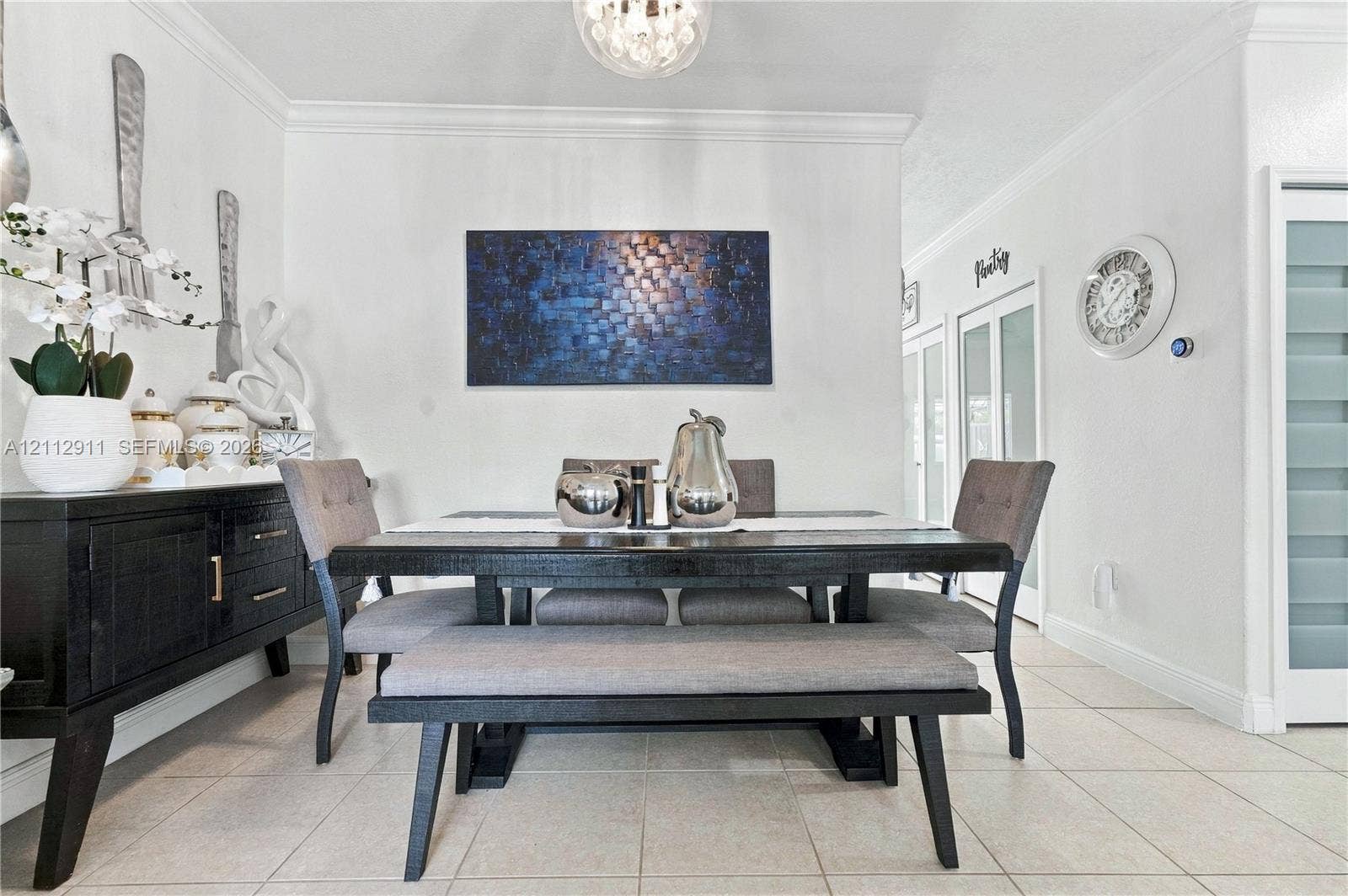 217 SW 15th Place, Homestead, FL 33030 Dining area featuring neutral tile flooring, crown molding, and a spherical glass-shade pendant light