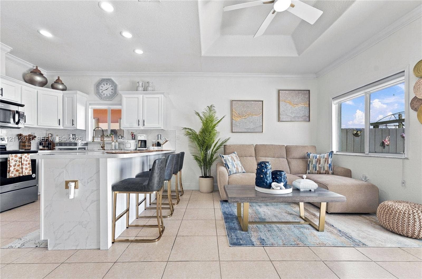217 SW 15th Place, Homestead, FL 33030 Open-concept kitchen featuring white shaker-style cabinetry, an island with a stone-finish countertop, recessed lighting, and a tray ceiling with a center-mounted ceiling fan