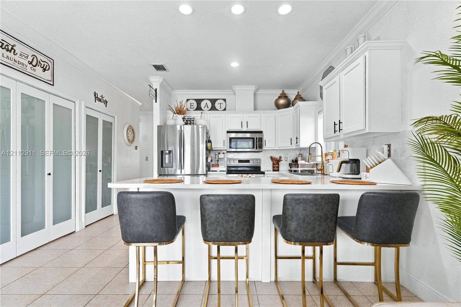 217 SW 15th Place, Homestead, FL 33030 Kitchen featuring white cabinetry, solid-surface countertops, stainless steel appliances, recessed lighting, and dual frosted-glass pantry doors