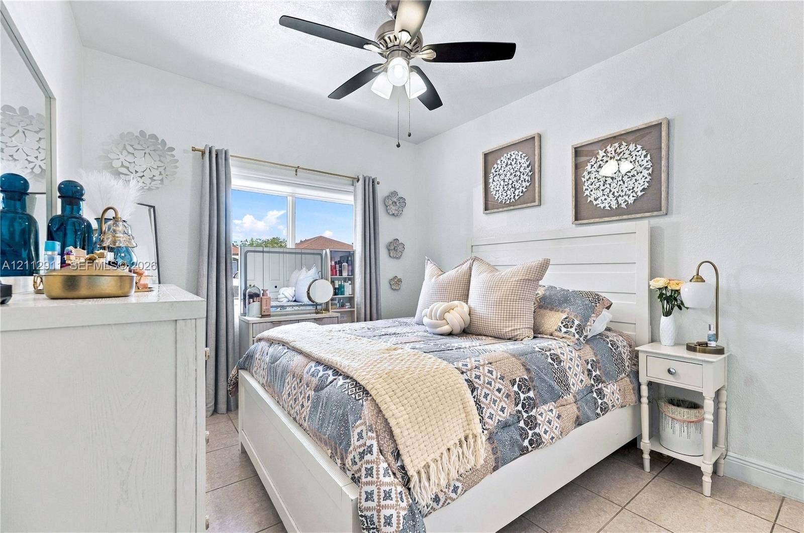 217 SW 15th Place, Homestead, FL 33030 Bedroom featuring light-toned tile flooring, a multi-blade ceiling fan with integrated lighting, and a window with horizontal blinds
