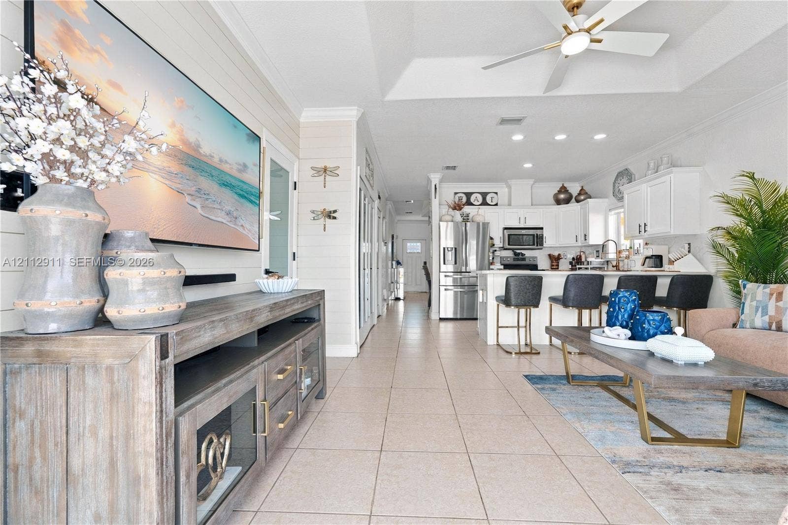 217 SW 15th Place, Homestead, FL 33030 Open-concept floor plan featuring a trey ceiling, tile flooring, shiplap wall accents, recessed lighting, and a kitchen island with built-in cabinetry