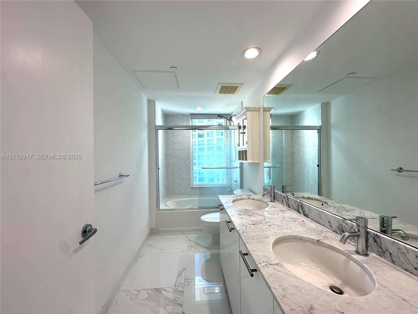 951 Brickell Avenue, #2601, Miami, Miami, FL 33131 Bathroom featuring a dual-sink vanity with stone-surfaced countertops, expansive wall-to-wall mirror, recessed lighting, and a bathtub with a glass sliding enclosure