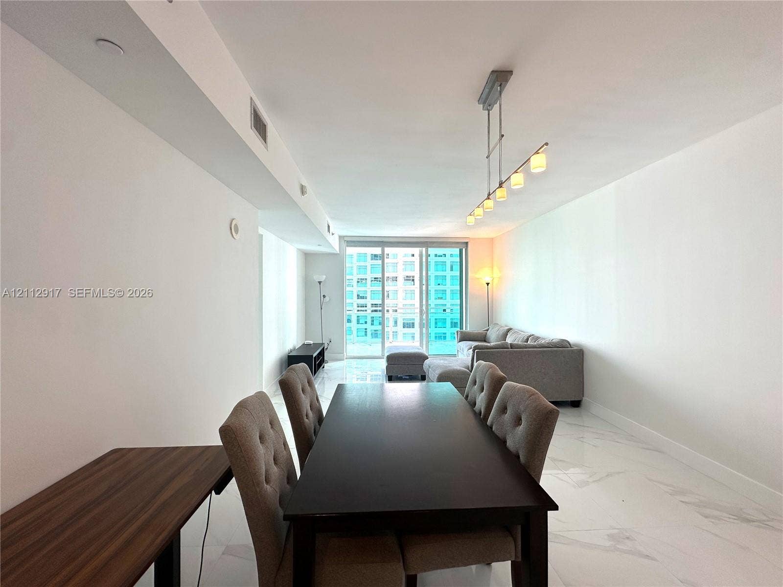 951 Brickell Avenue, #2601, Miami, Miami, FL 33131 Polished stone flooring, linear multi-light pendant fixture, and floor-to-ceiling glass sliding doors