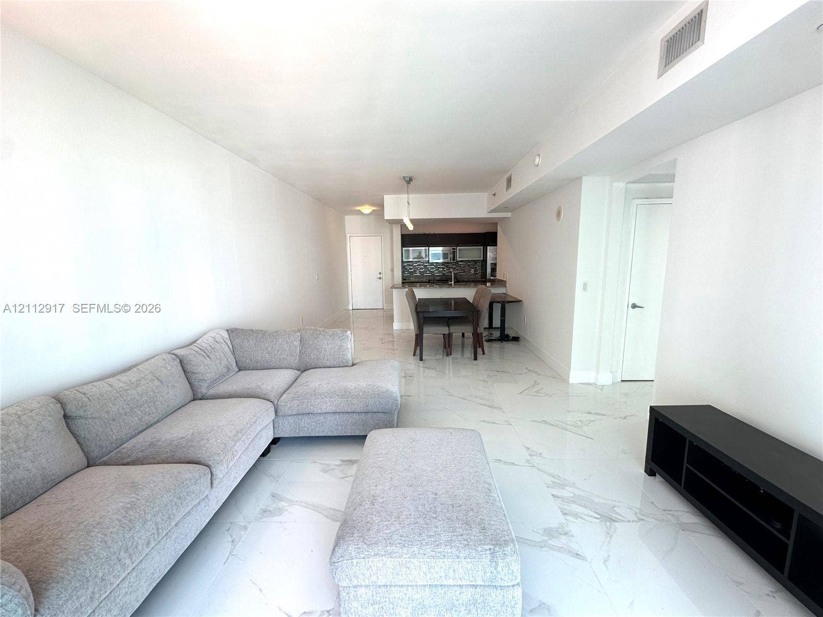 951 Brickell Avenue, #2601, Miami, Miami, FL 33131 Open-concept floor plan featuring large-format polished flooring with veined detailing and a built-in kitchen peninsula