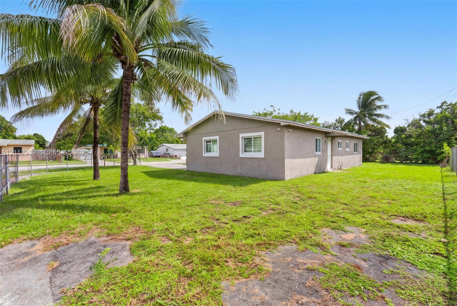 2120 NW 28th Terrace, Fort Lauderdale, FL 33311 Stucco exterior siding, single-story profile, multi-pane windows, and mature palm trees set on a grass lot