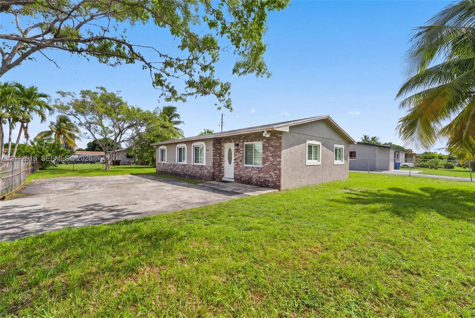 2120 NW 28th Terrace, Fort Lauderdale, FL 33311 Single-story exterior featuring a partial brick facade, stucco finish, paved driveway, and multiple casement windows