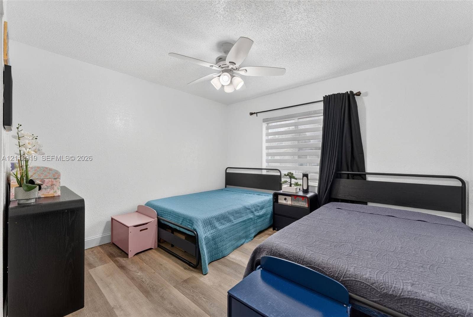 2120 NW 28th Terrace, Fort Lauderdale, FL 33311 Interior room featuring wood-finish flooring, a ceiling fan with integrated lighting, textured ceiling, a window with horizontal blinds, and a built-in electrical outlet
