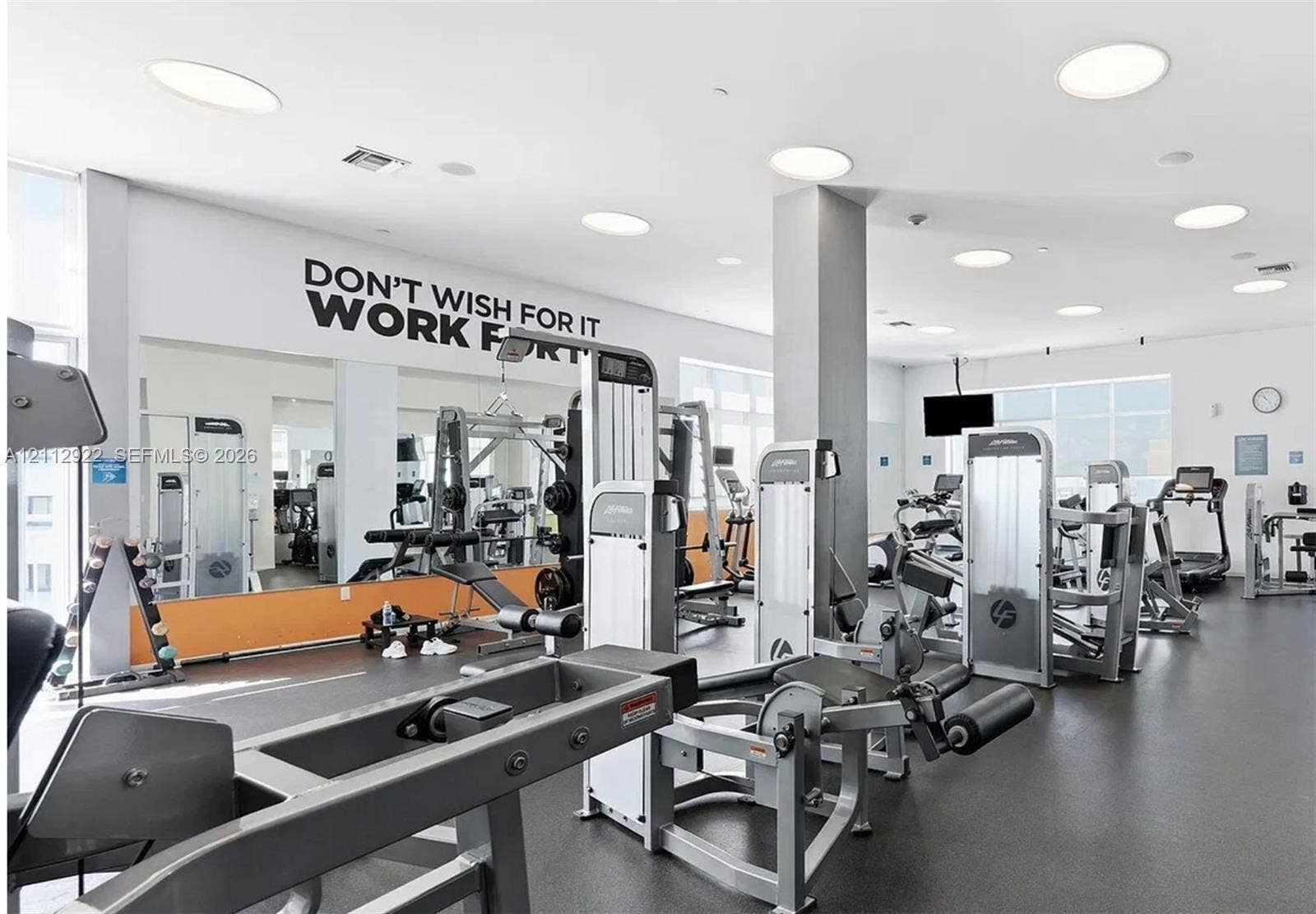 Fitness center featuring recessed ceiling lighting, large-scale wall mirrors, and rubber flooring