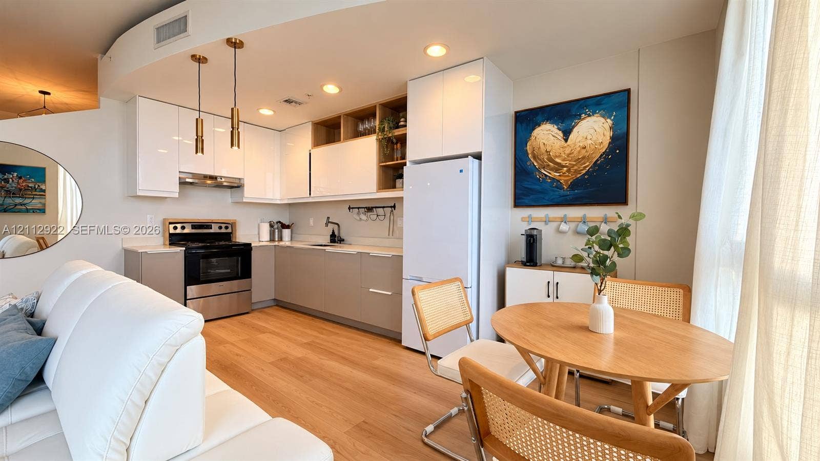 Modern kitchen featuring two-tone cabinetry, wood-finish flooring, recessed lighting, metallic pendant fixtures, and stainless steel appliances