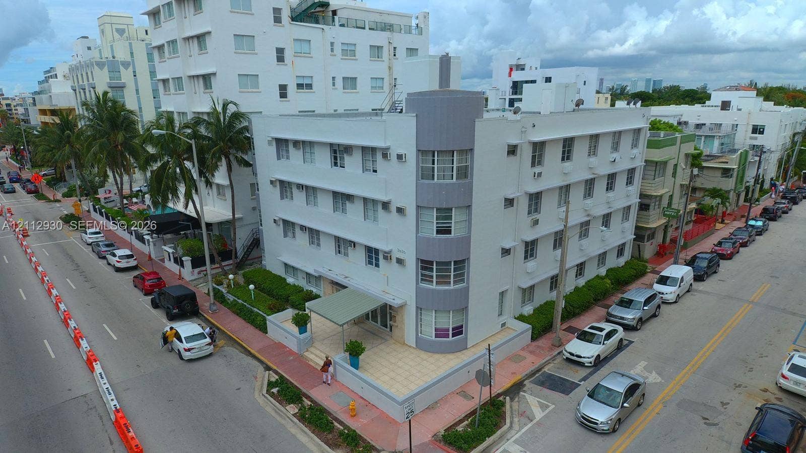 3030 Collins Avenue, #1G, Miami Beach, FL 33140 Multi-story Art Deco building featuring a curved corner facade, multi-pane ribbon windows, and a paved street-level entrance