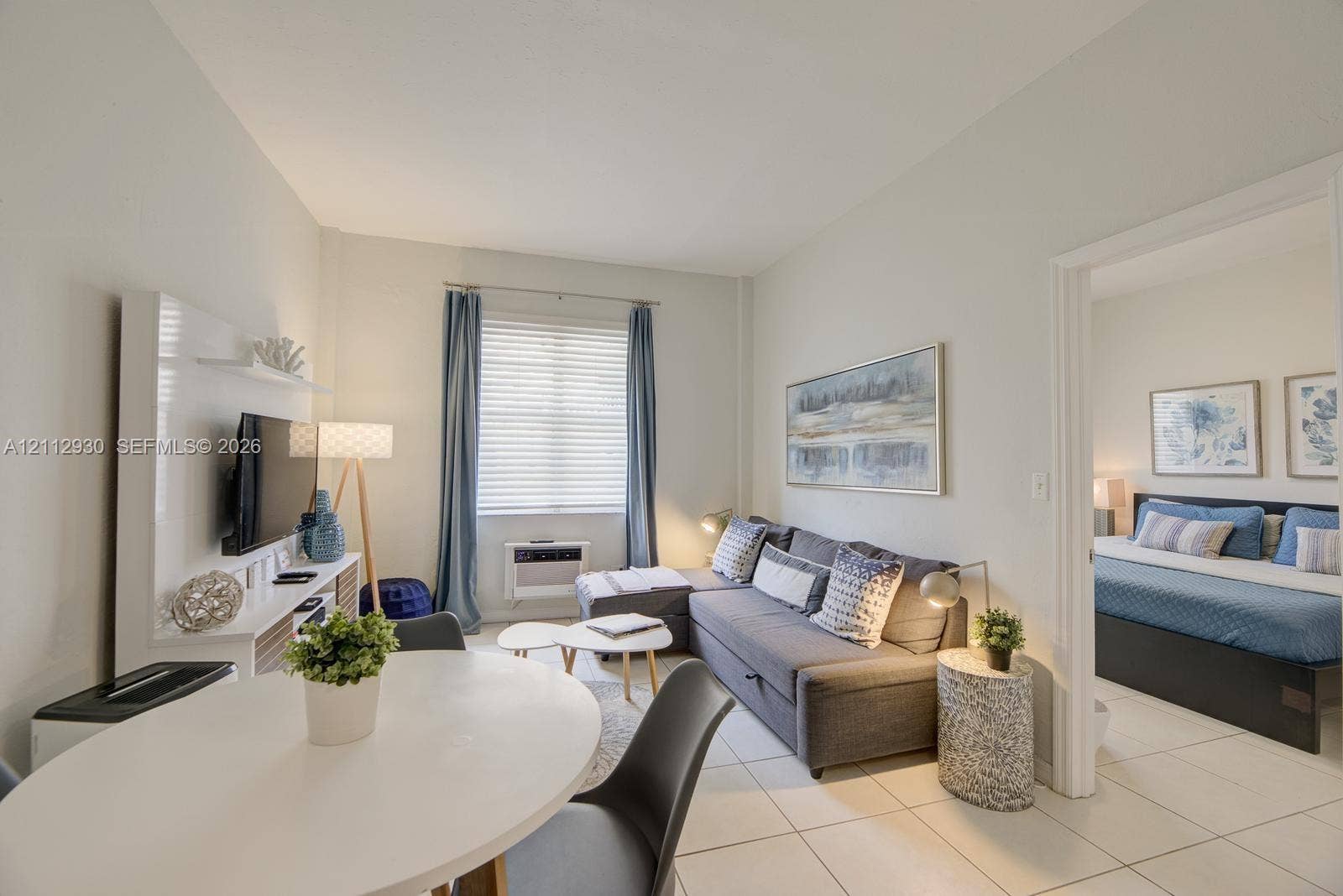 3030 Collins Avenue, #1G, Miami Beach, FL 33140 Interior living space featuring large-format tile flooring, bright neutral wall tones, and a wall-mounted media console