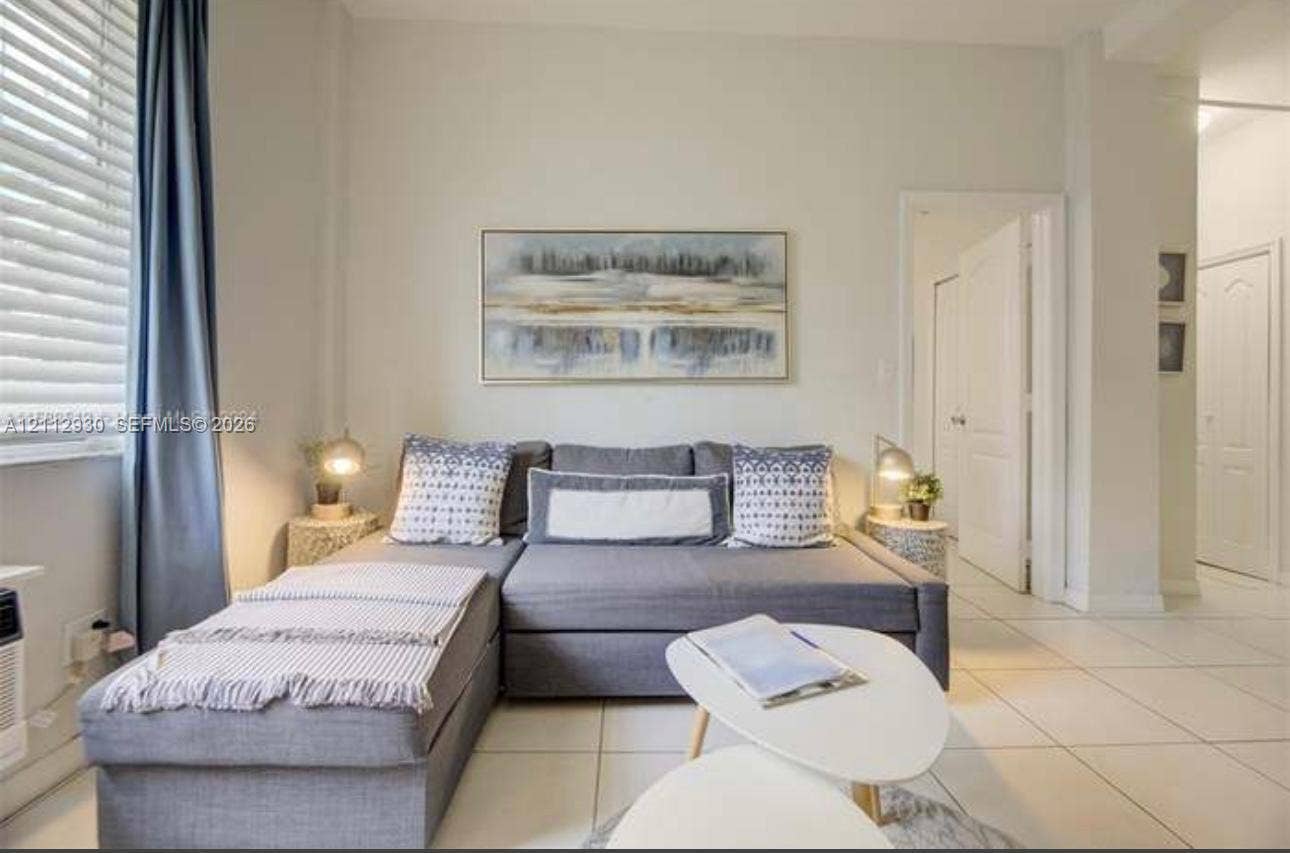 3030 Collins Avenue, #1G, Miami Beach, FL 33140 Living area featuring neutral-toned walls, large-format tile flooring, and multi-panel window blinds