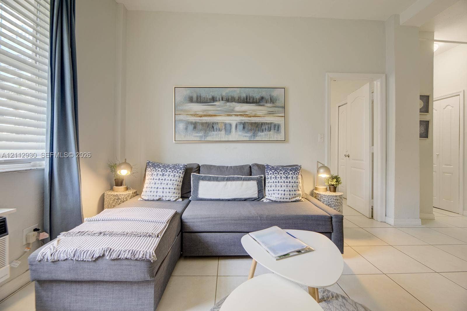 3030 Collins Avenue, #1G, Miami Beach, FL 33140 Interior space featuring large-format tile flooring, horizontal slat window blinds, and paneled interior doors