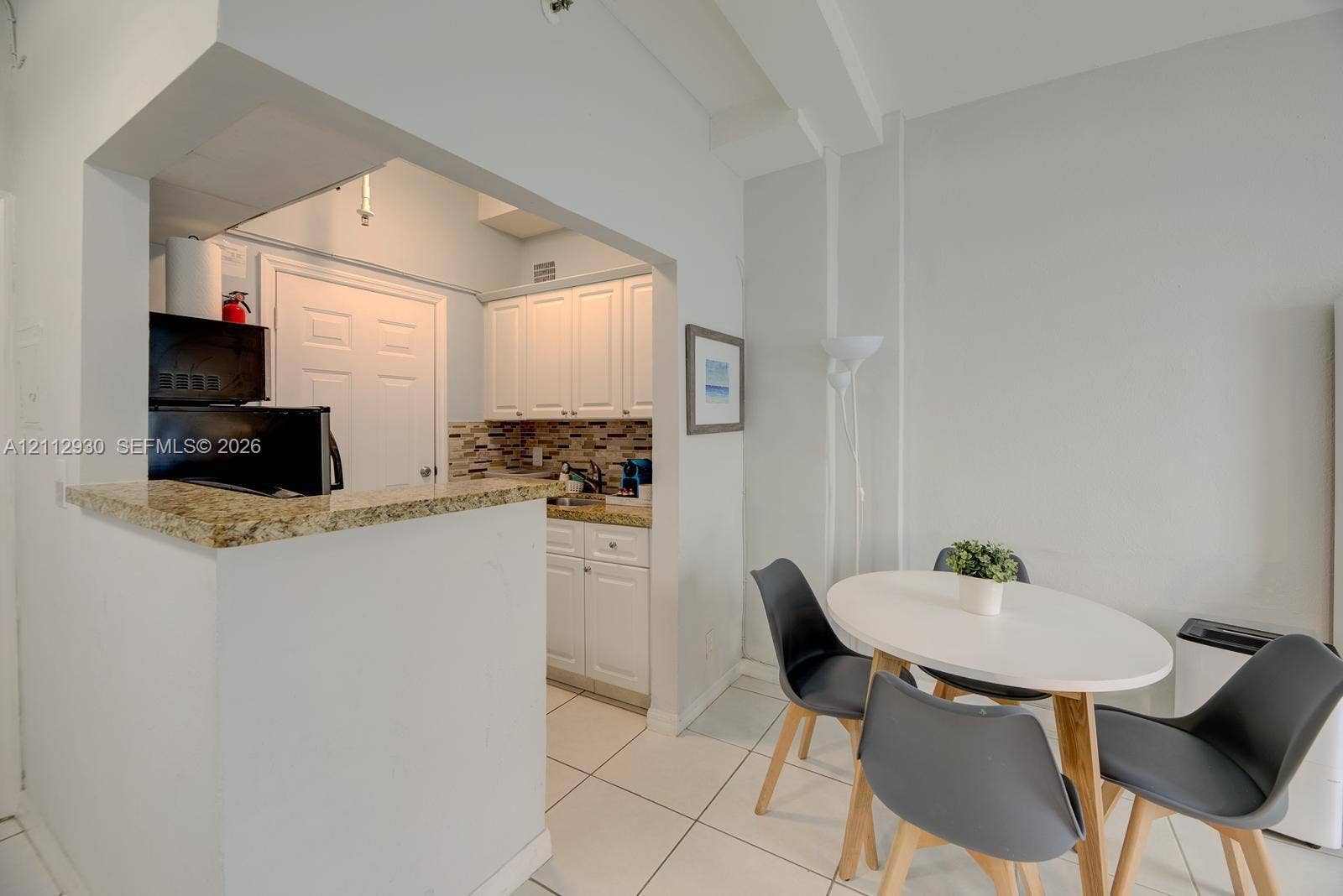 3030 Collins Avenue, #1G, Miami Beach, FL 33140 Kitchen featuring white cabinetry, stone-finish countertops, tile backsplash, and light tile flooring
