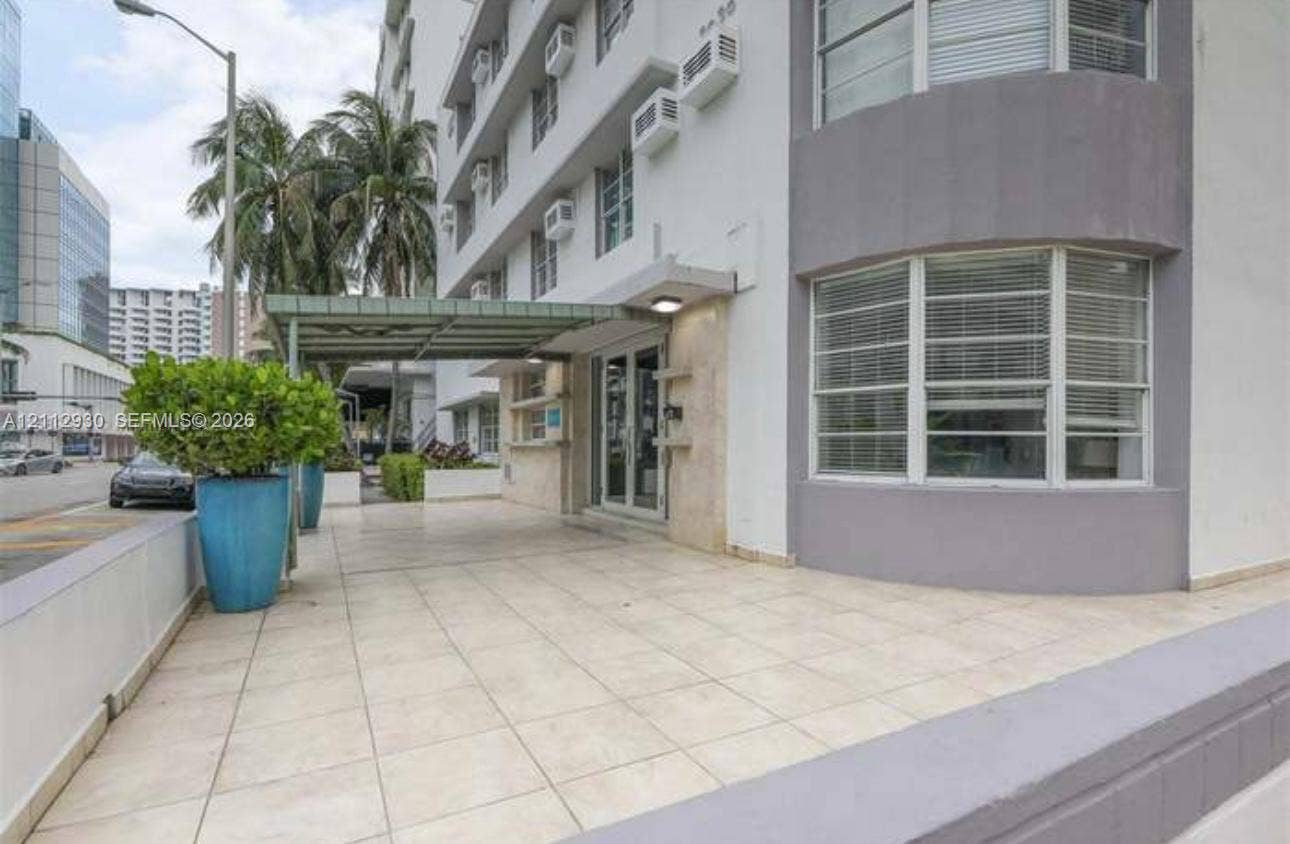 3030 Collins Avenue, #1G, Miami Beach, FL 33140 Exterior entrance featuring a covered porte-cochre, light-toned ceramic tile flooring, a glass-paneled entry door, and bay-style windows
