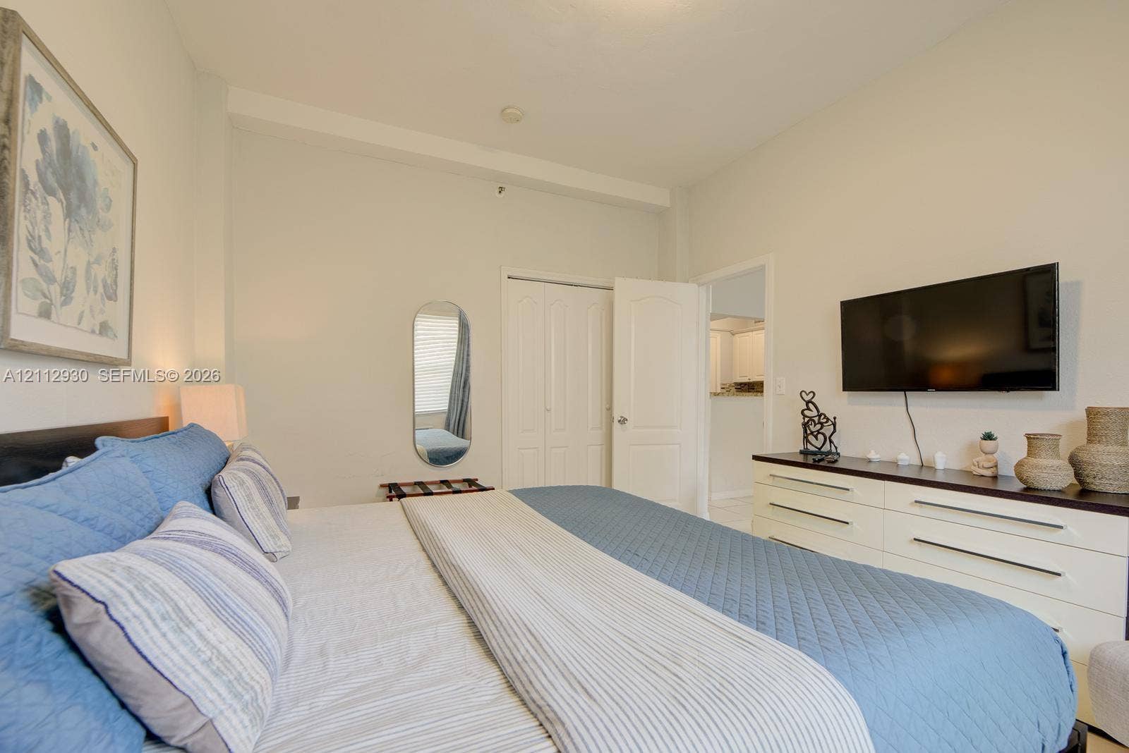3030 Collins Avenue, #1G, Miami Beach, FL 33140 Neutral-toned interior featuring high ceilings, a reach-in closet with double-panel doors, and a wall-mounted television