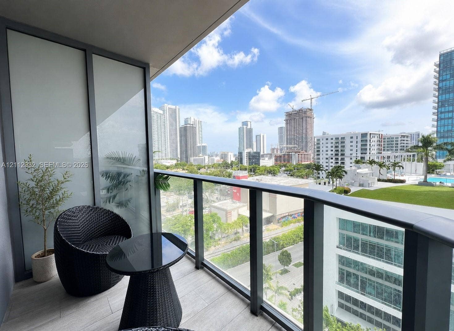 121 NE 34th Street, #903, Miami, FL 33137 Private covered balcony featuring ceramic tile flooring, a glass panel railing, and frosted privacy screening