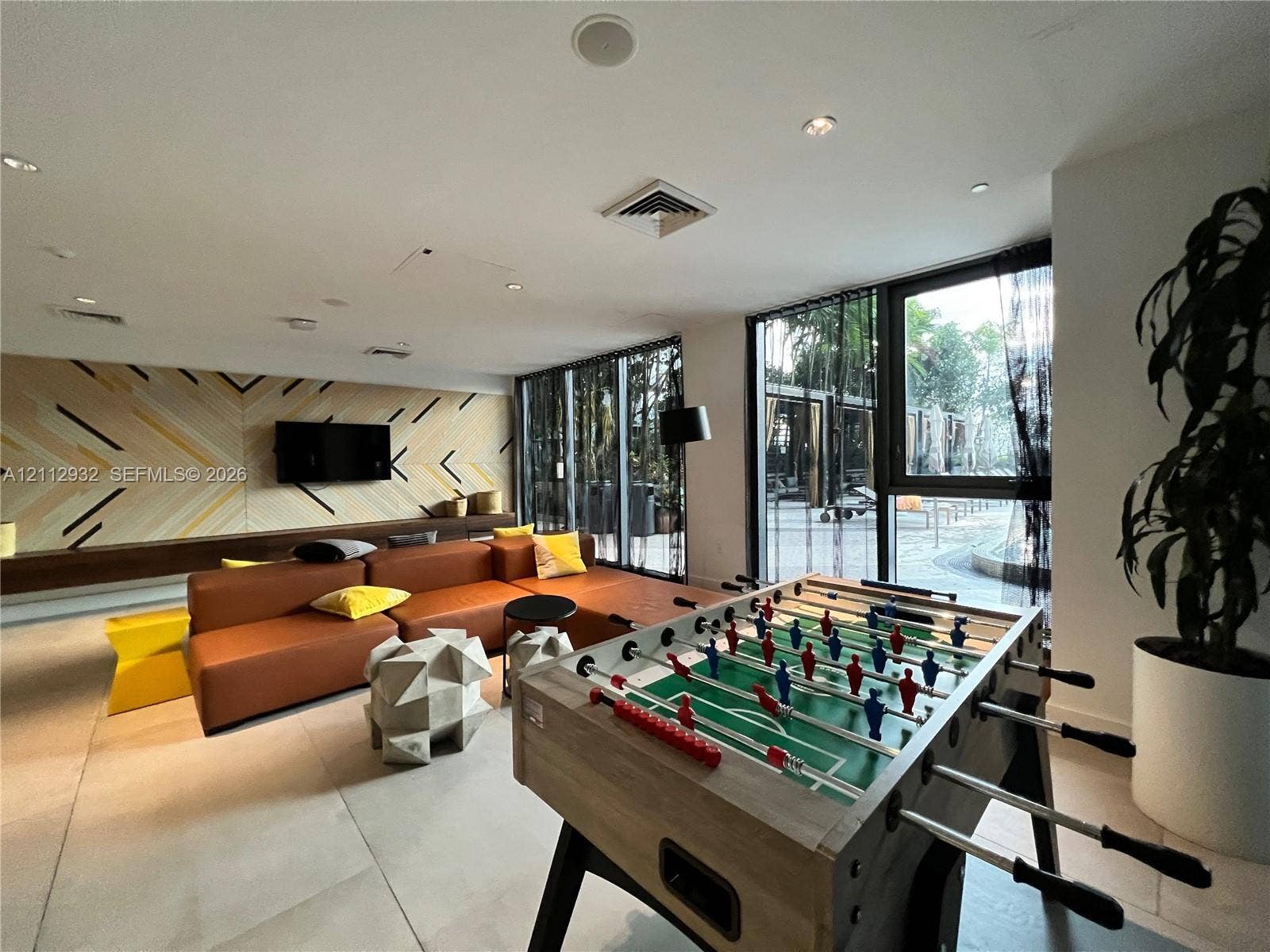 121 NE 34th Street, #903, Miami, FL 33137 Large-format tile flooring, geometric wall paneling, built-in wooden media console, and floor-to-ceiling windows