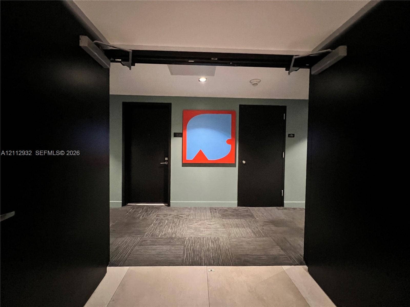 121 NE 34th Street, #903, Miami, FL 33137 Hallway featuring high-contrast black paneled doors, square-patterned carpet, and a recessed ceiling light