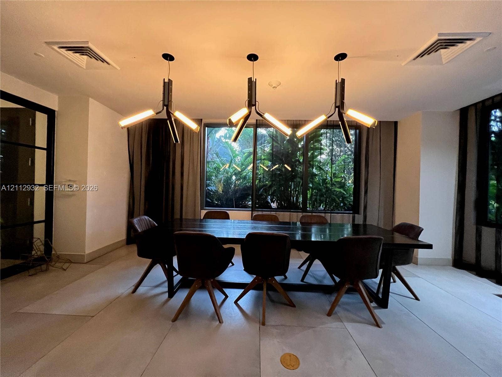 121 NE 34th Street, #903, Miami, FL 33137 Large format tile flooring, floor-to-ceiling windows with dark framing, and three architectural linear-style pendant light fixtures