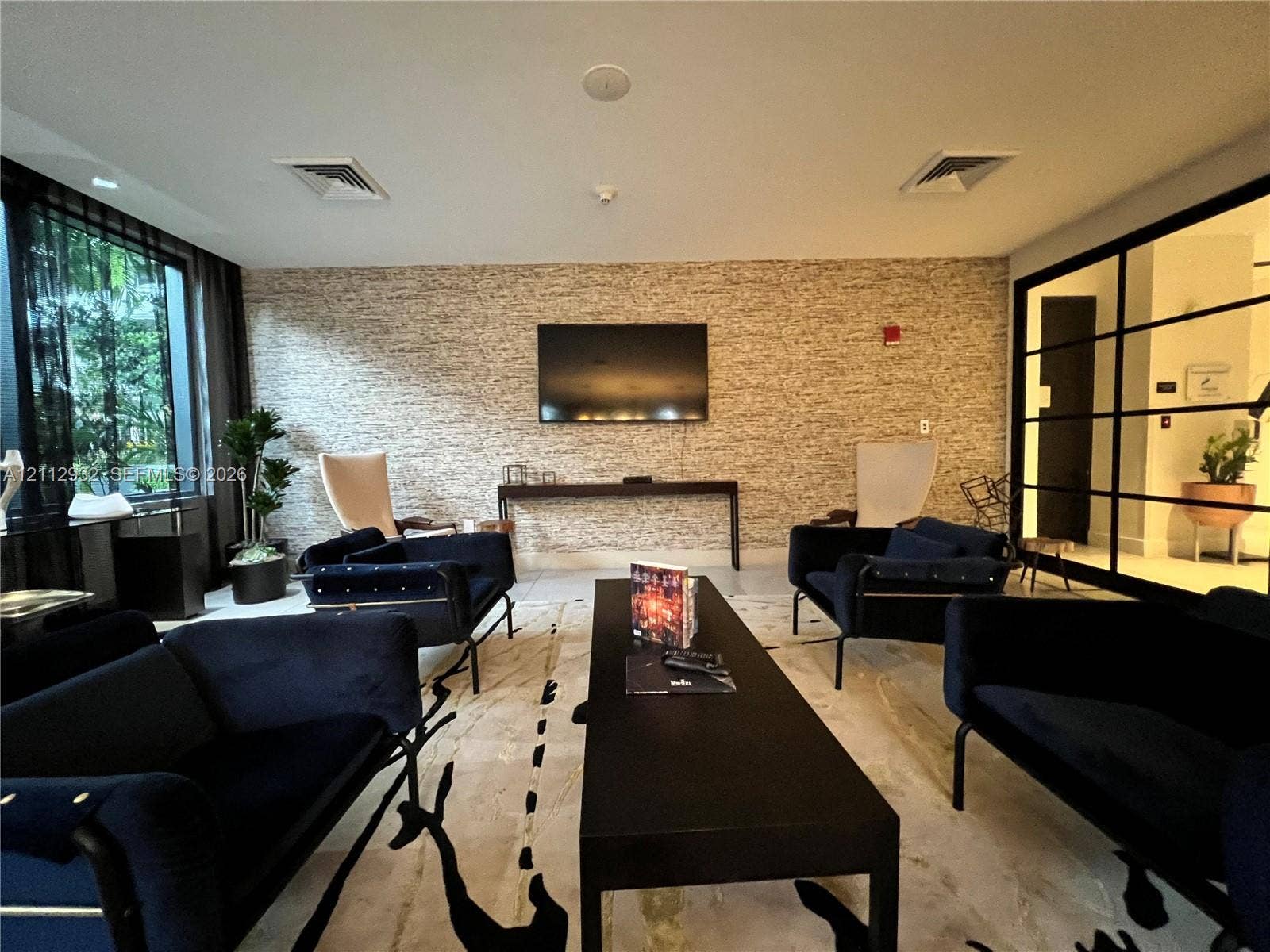 121 NE 34th Street, #903, Miami, FL 33137 Textured stone-finish accent wall, floor-to-ceiling windows, and industrial-style metal-framed glass partition
