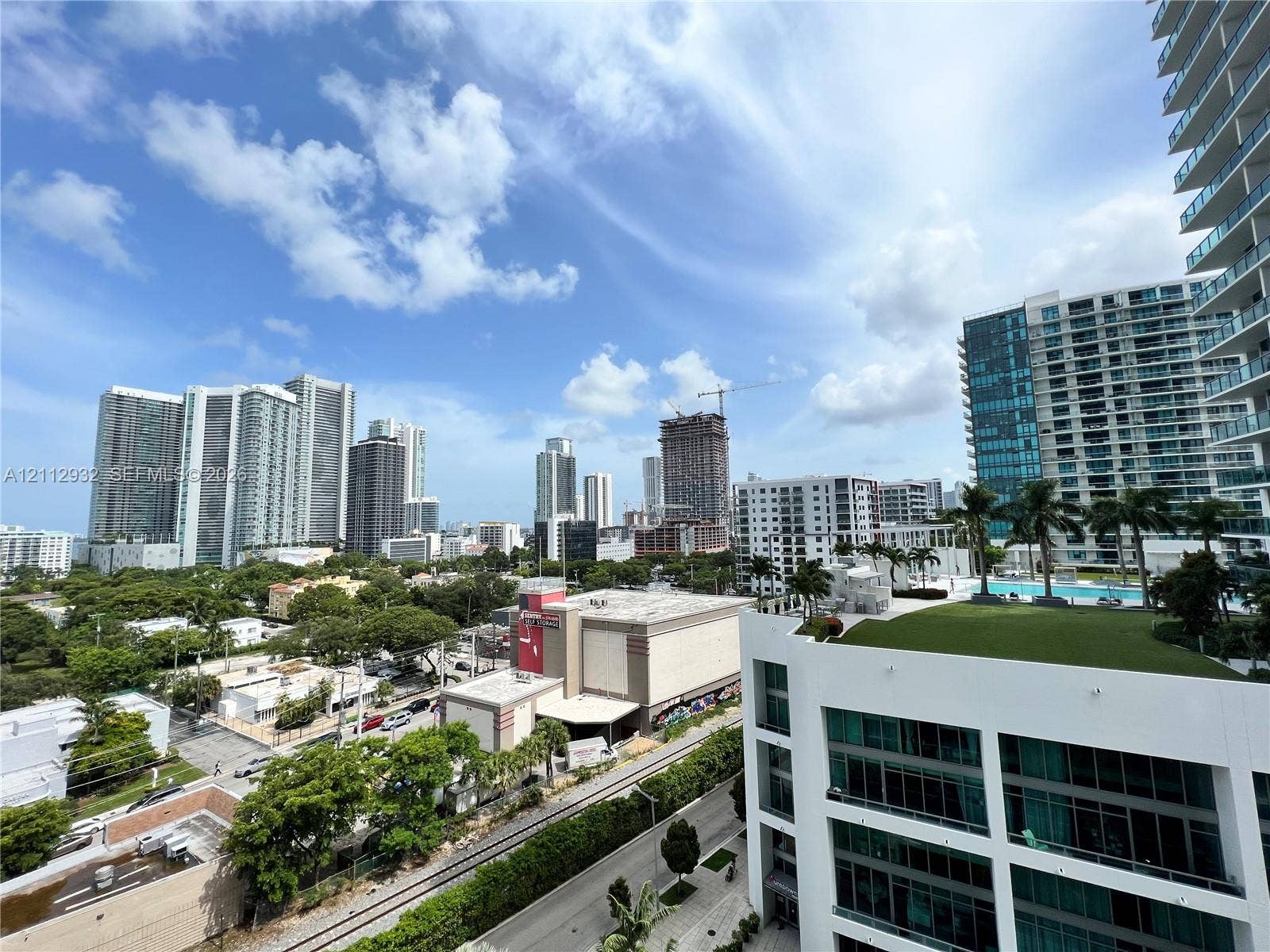 121 NE 34th Street, #903, Miami, FL 33137 Elevated terrace featuring a green roof and glass balcony railings, set against a cityscape backdrop