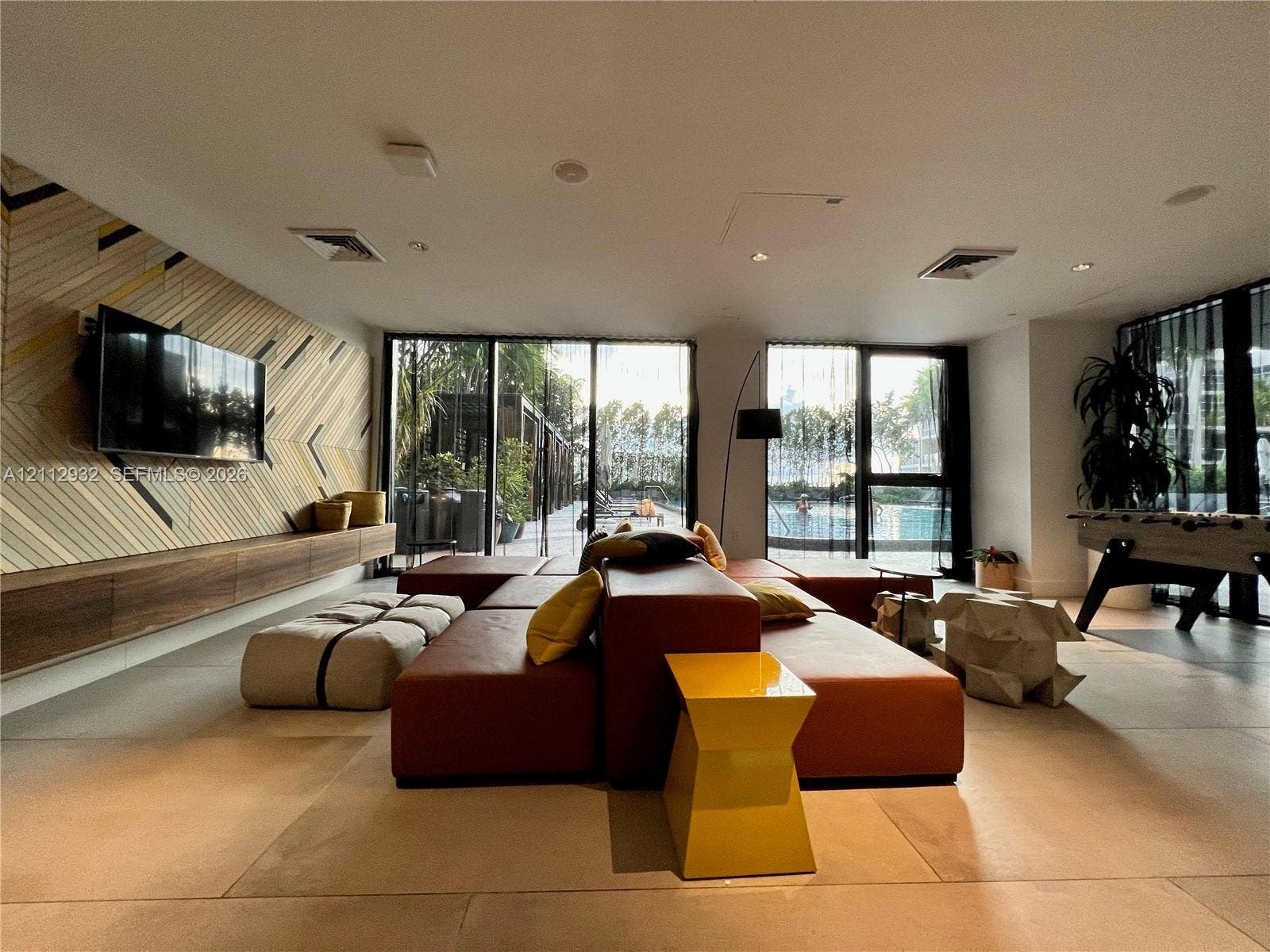 121 NE 34th Street, #903, Miami, FL 33137 Large-format tile flooring, floor-to-ceiling glass panel doors, and custom wood-finish wall paneling with an integrated floating cabinetry console