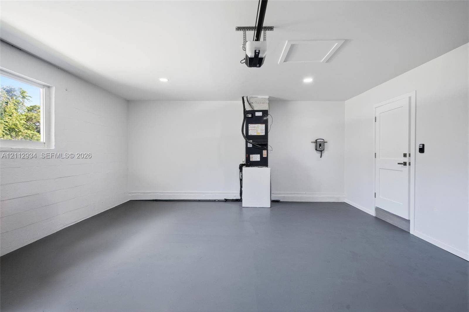 14620 SW 83rd Avenue, Palmetto Bay, Palmetto Bay, FL 33158 Finished garage featuring gray epoxy flooring, white painted walls, recessed lighting, and a solid-core interior door