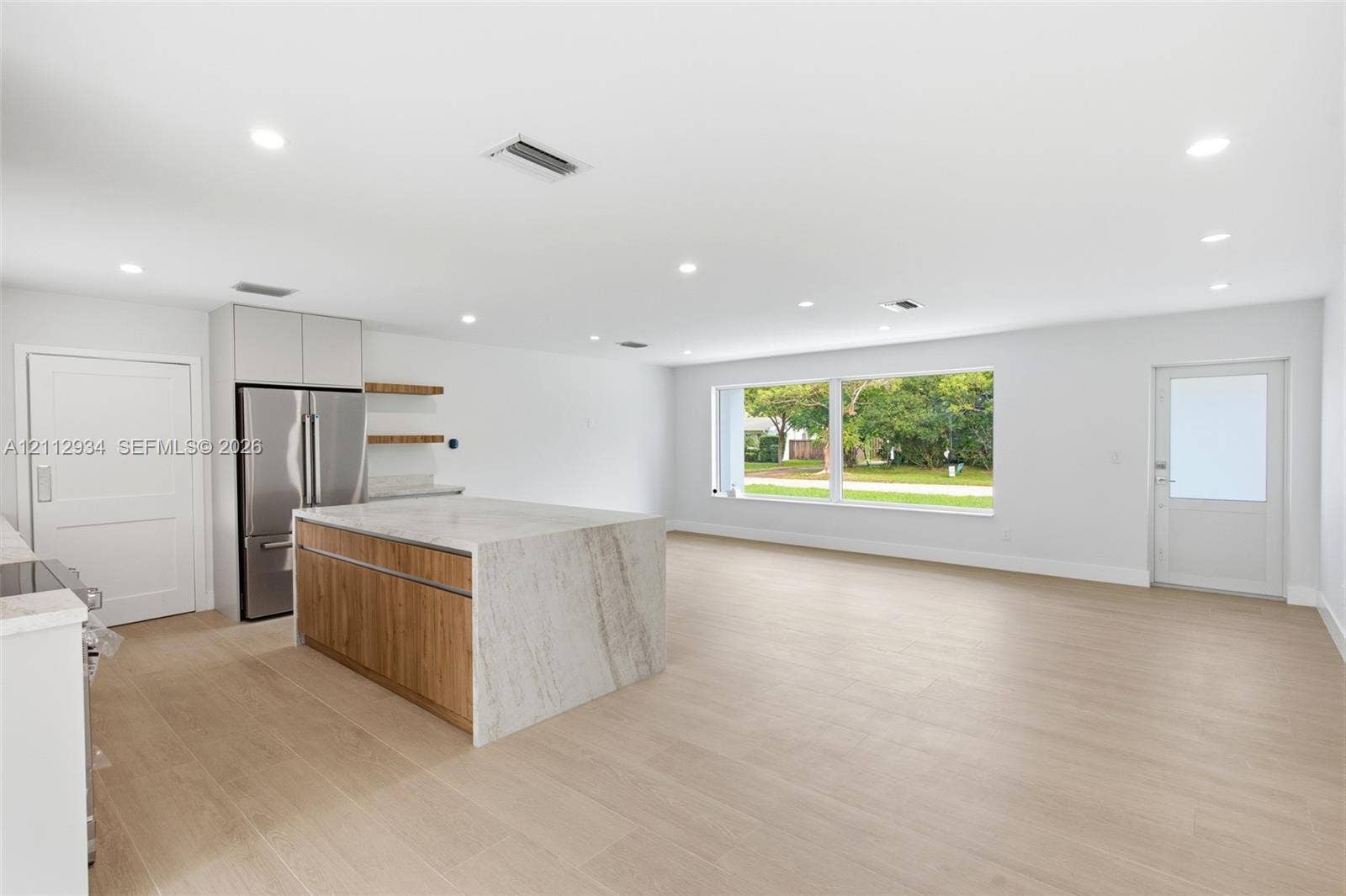 14620 SW 83rd Avenue, Palmetto Bay, Palmetto Bay, FL 33158 Open-concept kitchen featuring an island with stone-finish waterfall countertops and wood-finish cabinetry, stainless steel refrigerator, recessed lighting, and wood-finish flooring throughout