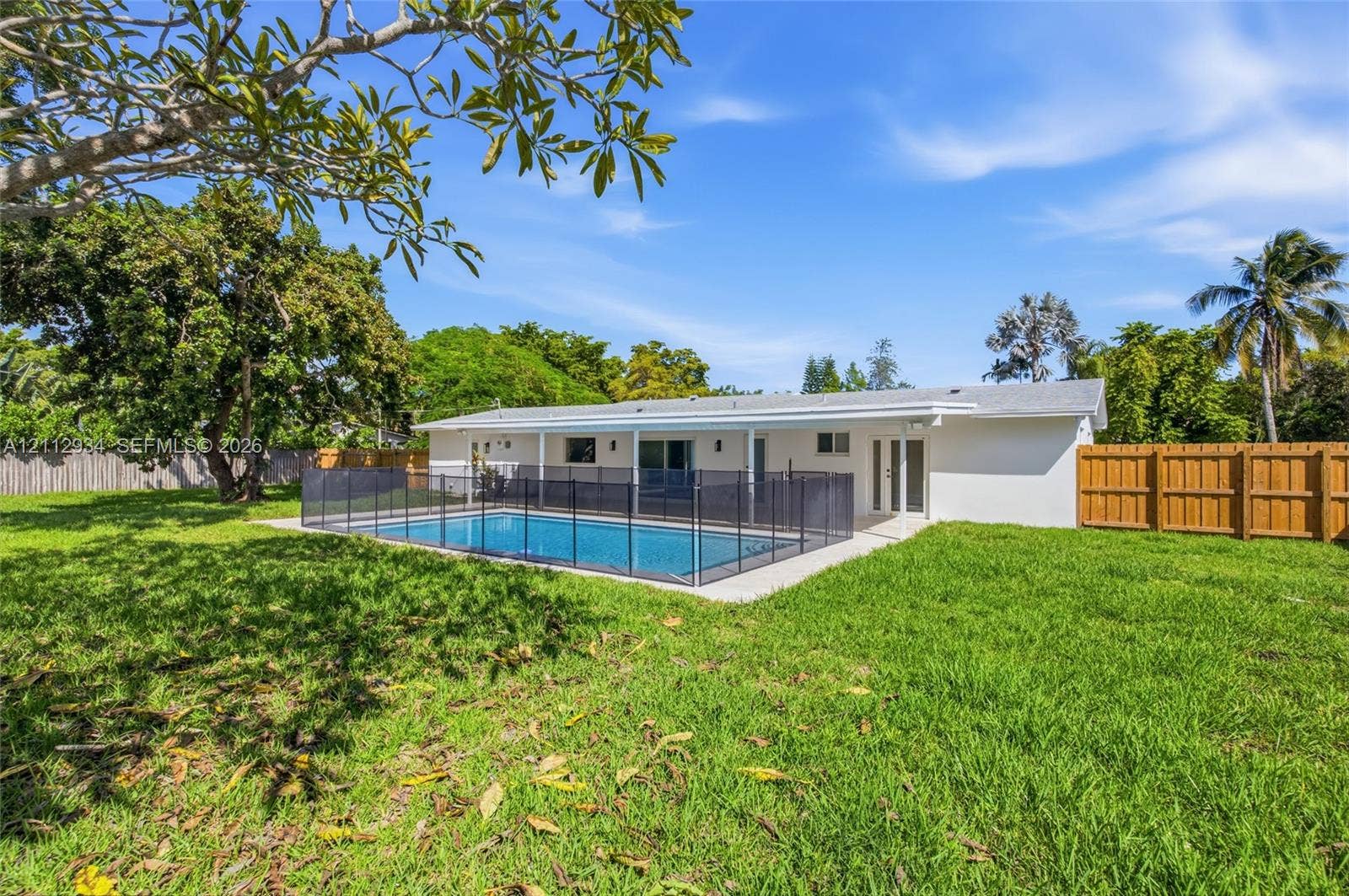 14620 SW 83rd Avenue, Palmetto Bay, Palmetto Bay, FL 33158 Rear exterior featuring a covered patio, a rectangular swimming pool with a removable safety fence, a concrete pool deck, and a fenced backyard
